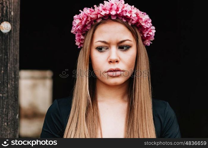 Beautiful portrait of a blonde girl with a pink wreath of flowers on her head