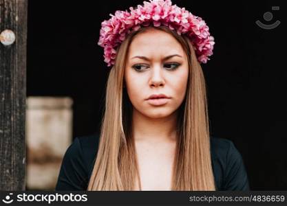 Beautiful portrait of a blonde girl with a pink wreath of flowers on her head