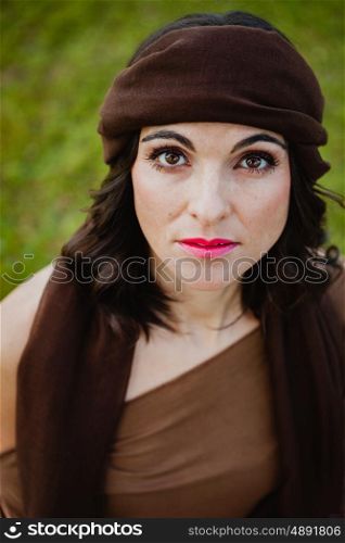 Beautiful portrait of a brunette woman with a brown bandana in her hair looking at camera