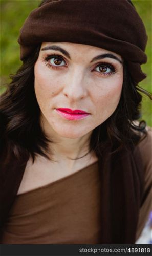 Beautiful portrait of a brunette woman with a brown bandana in her hair looking at camera