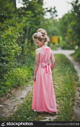 Beautiful portrait of a girl in evening dress among the garden.. Girl in long pink dress posing on nature background 6649.