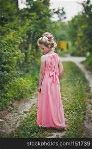 Beautiful portrait of a girl in evening dress among the garden.. Girl in long pink dress posing on nature background 6649.