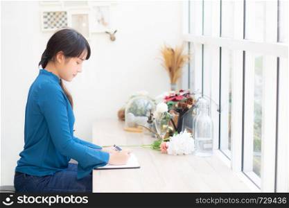Beautiful portrait young asia woman writer writing on notebook or diary with happy, lifestyle of asian girl is student, female planning working, education and business concept.