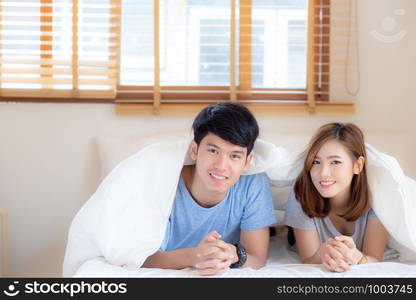 Beautiful portrait young asian couple relax and satisfied together in bedroom at home, family lying on bed confident with cheerful and happy with relationship, man and woman dating.