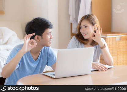 Beautiful portrait young asian couple working laptop with smile and happy sitting in bedroom, man and woman using notebook computer with excited and satisfied, business and success concept.