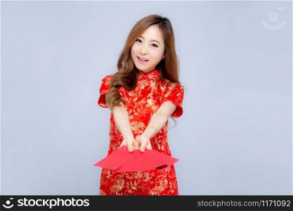 Beautiful portrait young asian woman cheongsam dress smiling holding red envelope on white background, beauty asia girl wear qipao celebrate with exciting, happy Chinese New Year, holiday concept.