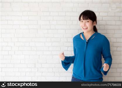 Beautiful portrait young asian woman gesture happy and success with victory on white cement concrete background, girl confidence and excited for expression victory and proud, lifestyle concept.