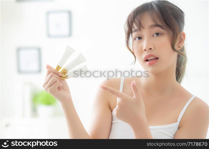 Beautiful portrait young asian woman holding and pointing presenting cream or lotion product, beauty asia girl show cosmetic makeup and moisturizing for skin care, healthy and wellness concept.