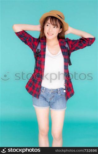Beautiful portrait young asian woman holding hat smile expression confident enjoy summer holiday isolated blue background, model girl fashion having backpack, travel concept.