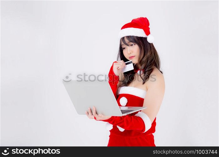 Beautiful portrait young asian woman in Santa thinking idea and holding credit card and laptop computer for shopping online in Christmas holiday isolated on white background, girl purchase and pay.