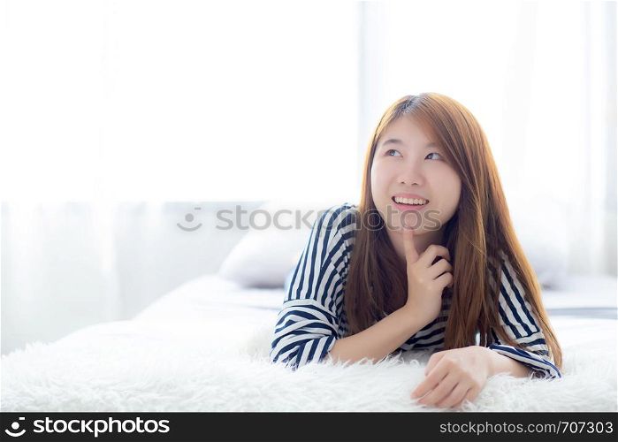 Beautiful portrait young asian woman lying and smile while wakeup with sunrise at morning, girl thinking idea something lifestyle and relax concept.