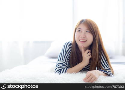 Beautiful portrait young asian woman lying and smile while wakeup with sunrise at morning, girl thinking idea something lifestyle and relax concept.