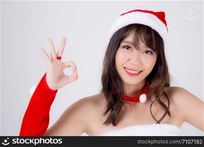 Beautiful portrait young asian woman Santa costume smiling gesture ok sign with happy in holiday xmas, beauty asia girl cheerful and happiness celebrating in Christmas isolated on white background.