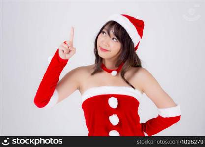Beautiful portrait young asian woman Santa costume smiling present pointing something in xmas holiday, model asia girl cheerful and happiness celebrating in Christmas isolated on white background.