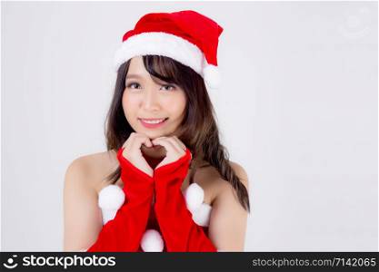 Beautiful portrait young asian woman Santa costume wear hat smiling gesture heart with hand in holiday xmas, beauty model asia girl cheerful celebrating in Christmas isolated on white background.