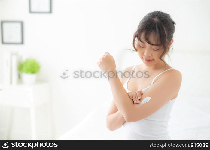 Beautiful portrait young asian woman smile applying sunscreen cream or lotion on skin care at bedroom, beauty asia girl using makeup and cosmetic for smooth and silky, wellness and health concept.