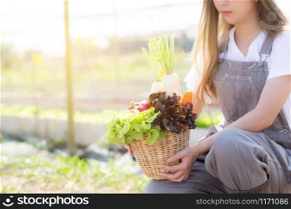 Beautiful portrait young asian woman smile harvest and picking up fresh organic vegetable garden in basket in the hydroponic farm, agriculture and cultivation for healthy food and business concept.