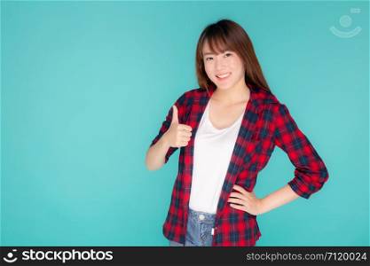 Beautiful portrait young asian woman smiling confident and excited summer holiday isolated blue background, beauty asia model girl gesture thumb up and cheerful with journey, travel concept.