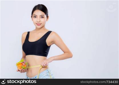 Beautiful portrait young asian woman smiling holding salad vegetable food and measuring waist for weight isolated on white background, girl diet with cellulite loss with tape measure, health care or wellness concept.