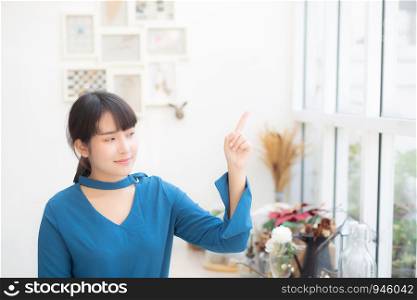 Beautiful portrait young asian woman smiling sitting at cafe pointing something, model girl happy with relax and resting, lifestyle concept.