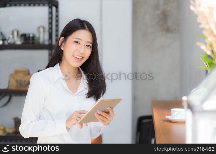 Beautiful portrait young asian woman using tablet computer in the coffee shop, businesswoman sitting looking tablet is work at cafe, communication concept.
