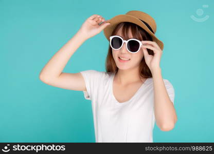 Beautiful portrait young asian woman wear hat and holding sunglasses smiling confident enjoy journey summer trip in vacation isolated on blue background, tourist asia girl cheerful with travel.