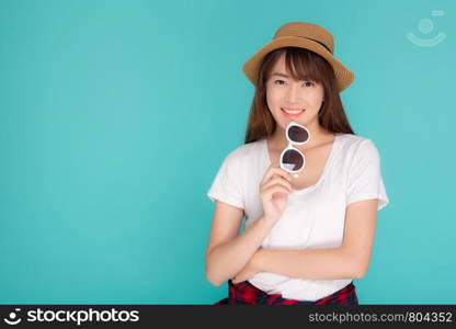 Beautiful portrait young asian woman wear hat and holding sunglasses smiling expression confident enjoy summer in vacation isolated on blue background, girl cheerful wear fashion travel concept.