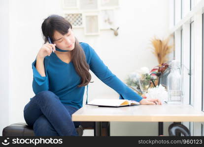 Beautiful portrait young asian woman writer smiling thinking idea and writing on notebook or diary with happy, lifestyle of asian girl is student, female planning working, education and business concept.