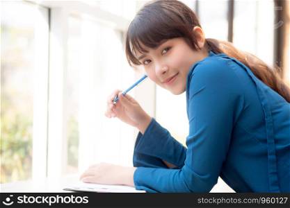 Beautiful portrait young asian woman writer smiling thinking idea and writing on notebook or diary with happy, lifestyle of asia girl is student, female planning working, education and business concept.