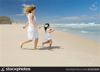Beautiful pregnant woman and her little daughter running to the sea