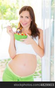 Beautiful pregnant woman eating salad, healthy lifestyle, young mother, female awaiting for a baby
