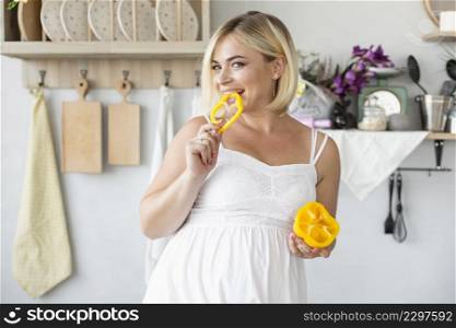 beautiful pregnant woman eating yellow pepper