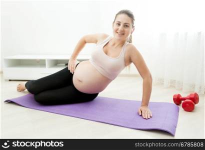 Beautiful pregnant woman exercising on fitness mat at home