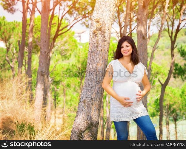 Beautiful pregnant woman having fun in summer park, young female expecting for a baby, happy motherhood, love concept