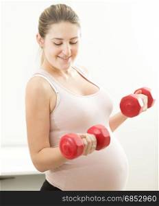 Beautiful pregnant woman lifting dumbbells
