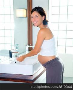 Beautiful pregnant woman on modern bathroom washing her hands