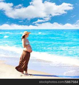 Beautiful pregnant woman on the beach with hat