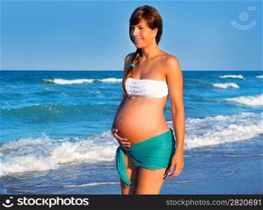 Beautiful pregnant woman walking on blue beach in summer vacation