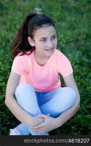 Beautiful preteen girl with blue eyes sitting on the grass