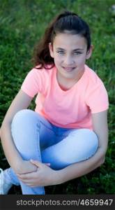 Beautiful preteen girl with blue eyes sitting on the grass