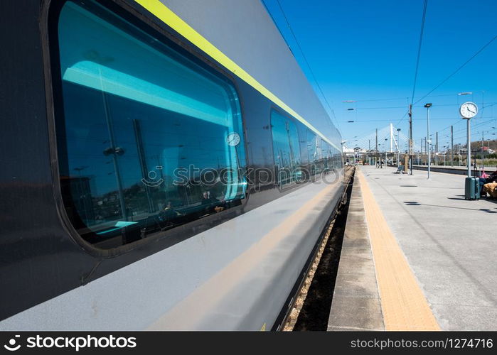 Beautiful railway station with modern commuter train at sunny day. Railroad outdoor platform