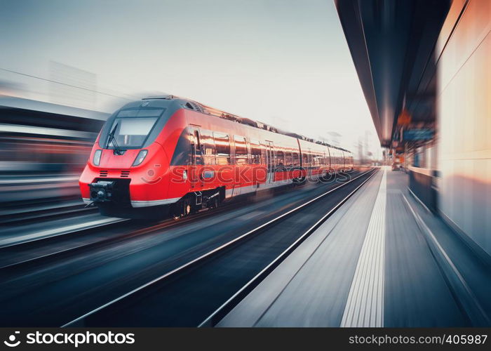 Beautiful railway station with modern high speed red commuter train with motion blur effect at sunset in Nuremberg, Germany. Railroad. Vintage toning. Railroad travel background, tourism. Industrial