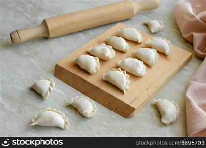 Beautiful raw stuffed dumplings on a wooden cutting board. Delicious fast food