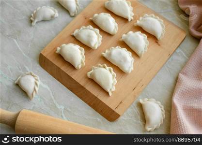 Beautiful raw stuffed dumplings on a wooden cutting board. Delicious fast food
