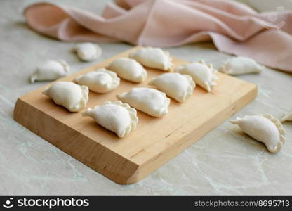 Beautiful raw stuffed dumplings on a wooden cutting board. Delicious fast food