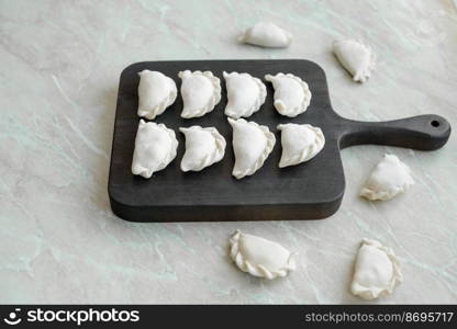 Beautiful raw stuffed dumplings on a wooden cutting board. Delicious fast food