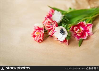 Beautiful red and white bouquet of tulips and anemones in kraft paper. The concept of spring and flowering. With copy space. Beautiful red and white bouquet of tulips and anemones in kraft paper. The concept of spring and flowering. With copy space.
