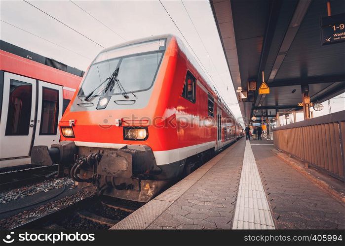 Beautiful red commuter train at railroad platform in the evening. Railway station at sunset in Nuremberg, Germany