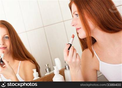 Beautiful red hair woman applying lipstick in the bathroom