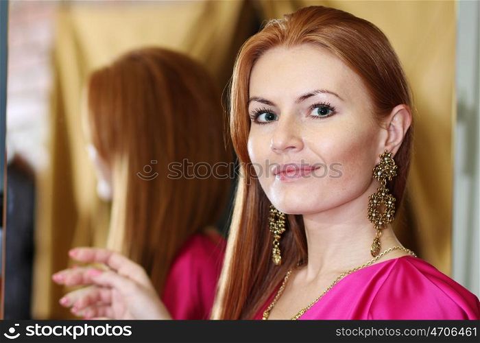 beautiful red-haired woman posing in front of a mirror